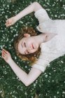Woman lying down on blossom covered grass, overhead view — Stock Photo
