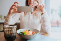 Donna che cattura foto di pasto vegano in ristorante — Foto stock