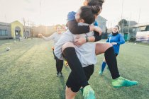 Football players jubilant and hugging on pitch — Stock Photo