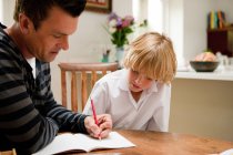 Padre aiutare figlio con i suoi compiti — Foto stock