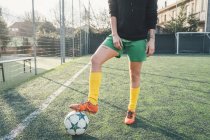 Jogador de futebol com pé na bola em campo — Fotografia de Stock