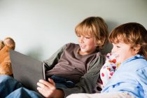 Dois meninos em uma cama, usando um tablet digital — Fotografia de Stock