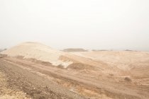 Vista de pista de sujeira no deserto contra fundo céu cinza — Fotografia de Stock