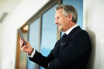 Senior-Geschäftsmann schaut im Büro auf Smartphone — Stockfoto