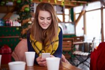 Молода жінка посміхається через текстове повідомлення на мобільному телефоні — стокове фото