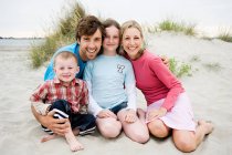 Молода сім'я сидить на пляжі, портрет — стокове фото