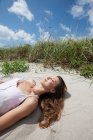 Молода жінка лежить спить на пляжі — стокове фото
