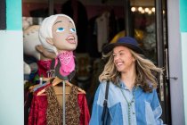Молода жінка залишає магазин одягу посміхаючись — стокове фото