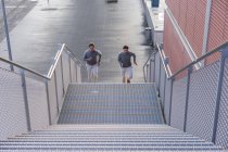 Jovens gêmeos do sexo masculino correndo até a escada da cidade — Fotografia de Stock