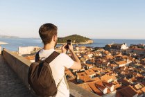 Mann fotografiert Meer über Dächern in dubrovnik, dubrovacko-neretvanska, kroatien, europa — Stockfoto