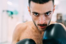 Портрет человека в боксёрских перчатках, смотрящего в камеру — стоковое фото