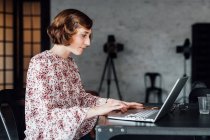 Mujer en el escritorio usando portátil en la oficina - foto de stock