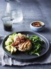 Still life with plate of chicken patty, avocado, onion and chilli jam — Stock Photo