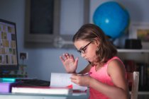 Молода дівчина робить домашнє завдання на столі — стокове фото