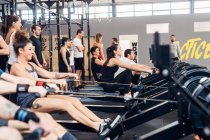 Large group of people using rowing machine in gym — Stock Photo
