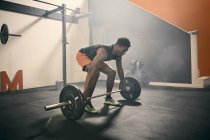 Man in gym weightlifting using barbell — Stock Photo