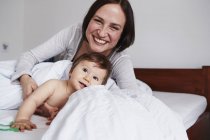 Mère et bébé fille se détendre sur le lit — Photo de stock