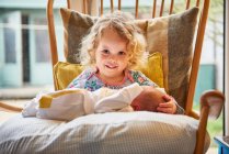 Female toddler and baby sister on chair, portrait — Stock Photo
