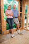 Mature couple standing in construction frame, portrait — Stock Photo