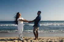 Пара стоящих на пляже, держащихся за руки, лицом к лицу — стоковое фото
