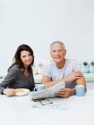Ältere Paare frühstücken und Zeitung lesen — Stockfoto