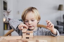 Portrait of young boy building structure with wooden building blocks — Stock Photo