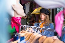 Молодая женщина, просмотр винтажной одежды в магазине бережливость — стоковое фото