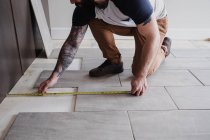 Vista ritagliata dell'uomo misurazione piastrelle del pavimento — Foto stock