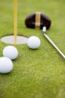 Golfbälle und Golfloch aus nächster Nähe — Stockfoto