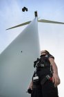 Низький кут зору інженера, який дивиться на вітрову турбіну — стокове фото