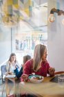 Frau isst in Café und benutzt Laptop — Stockfoto