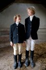 Boys wearing horse riding clothes in stable — Stock Photo