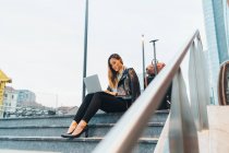 Бізнес-леді сидить на відкритому повітрі на сходах і використовує ноутбук — стокове фото