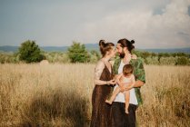 Jeune couple avec bébé fille sur champ d'herbe dorée, Arezzo, Toscane, Italie — Photo de stock