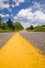 Franja de marcado amarillo en la carretera que va más allá del horizonte - foto de stock