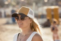 Портрет жінки носіння сонцезахисних окулярів і шапочка на пляжі — стокове фото
