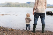Toddler and father at fjord water 's edge looking out, Aure, More og Romsdal, Noruega — Fotografia de Stock