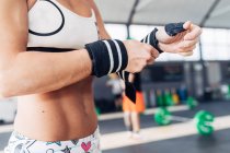 Cropped view of woman preparing for weightlifting, wearing gym gloves — Stock Photo