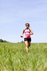 Senior mulher correndo através do campo com grama verde — Fotografia de Stock