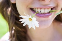 Close up of woman smiling with daisy in teeth — Stock Photo