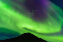 Aurora Borealis sobre la montaña, Narsaq, Vestgronland, Groenlandia - foto de stock