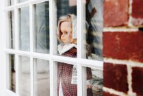 Кукла смотрит в окно, закрывается — стоковое фото