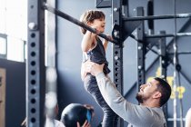 Father and daughter using pull up bar in gym — Stock Photo