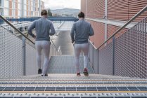 Вид сзади на близнецов, бегущих по городской лестнице — стоковое фото