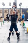 Männergewichtheben mit Kesselglocke in Turnhalle — Stockfoto