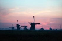 Siluetas de molinos de viento al atardecer idílico en Holanda - foto de stock