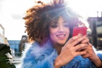 Ritratto di donna con afro guardando smartphone — Foto stock