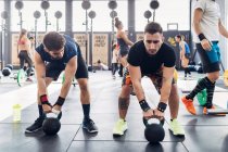 Men weightlifting with kettle bells in gym — Stock Photo