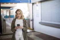 Frau benutzt Handy durch Fahrkartenschranke, Kapstadt, Südafrika — Stockfoto