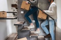 Couple carrying cardboard boxes up stairs — Stock Photo